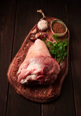 Raw pork knuckle, on a wooden chopping board, with spices, close-up, top view, no people,