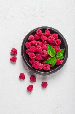 Taze ahududu, siyah bir tabakta, yapraklı, üst manzaralı, beyaz bir masada.,