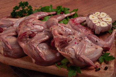 Kesme tahtasında çiğ bıldırcın eti, baharatlar ve otlarla, üst görünüm.,