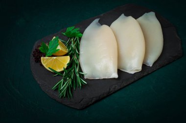 Taze mürekkep balığı bedeni, çiğ, üç leş, üst görünüm, siyah tahta üzerinde, insan yok.,