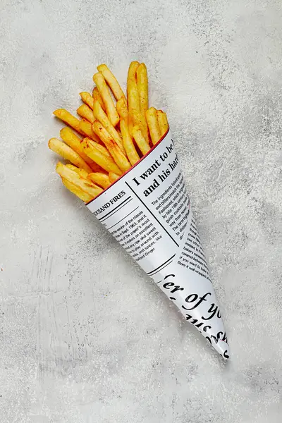 Fried French fries in a paper bag, on an abstract background, without people, in a rustic style, in a cone package, newspaper, a bag from the newspaper,