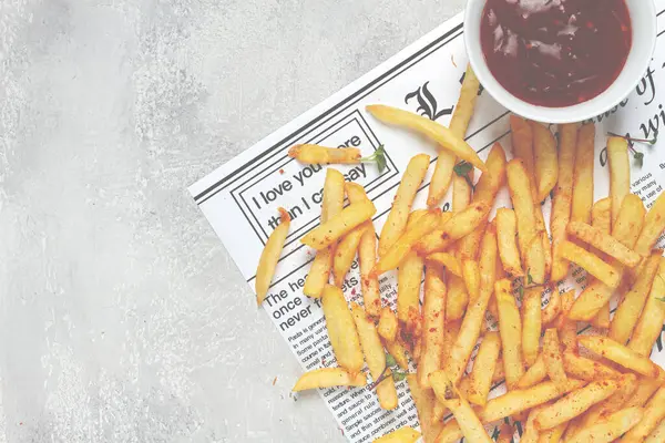 fried French fries, scattered on a newspaper, with red sauce, top view, no people,