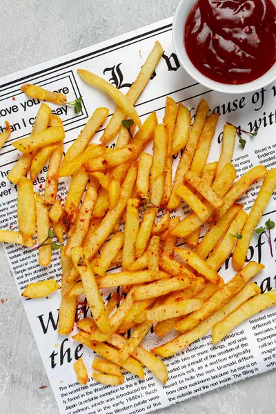 fried French fries, scattered on a newspaper, with red sauce, top view, no people,