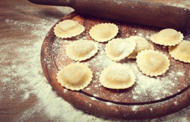 Taze çiğ, pişmemiş ravioli, kesme tahtasının üzerinde, hamuru için merdanesi olan, ahşap arka planı olan, insan olmayan,