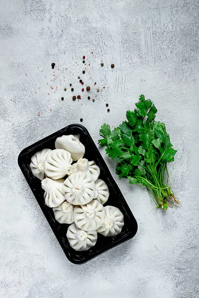 stock image freshly frozen, raw khinkali, in a black plastic container, top view, no people, Georgian cuisine,