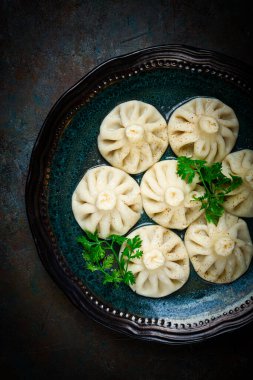 Yarısı yenmiş Khinkali, baharat ve otlarla dolu geleneksel bir Gürcü yemeği, gri bir tabakta, üst manzara, insan yok.,