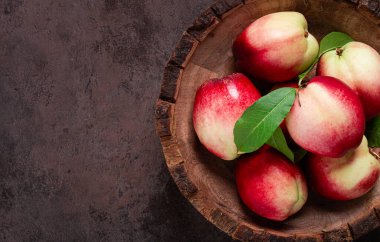 Olgun nektarin, ahşap bir tabakta, kahverengi arka plan, üst manzara, insan yok.,