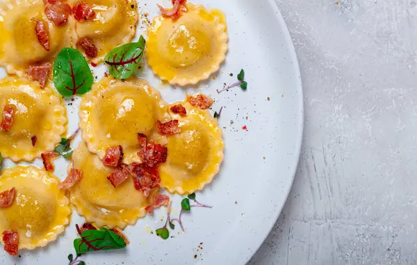 stock image fresh ravioli, with butter, spices and herbs, fried bacon, on the table, top view, light background, no people,