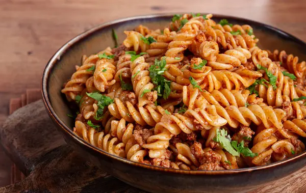 Donanmada makarna, kıymalı makarna, ahşap bir masada tabak, ev yapımı, fusilli makarna, insanlar olmadan.,