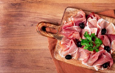 Kesme tahtasında dilimlenmiş jambon, zeytin ve otlarla, atıştırmalık, kahvaltı, insan yok.,