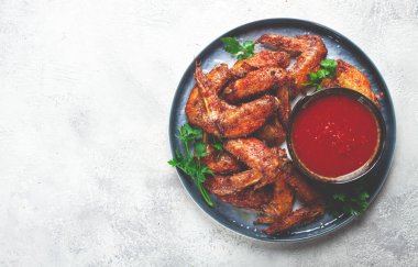 Fırında kızartılmış tavuk kanadı, baharatlı, domates soslu, tabakta, gri arka planda, insan yok, ev yapımı.,