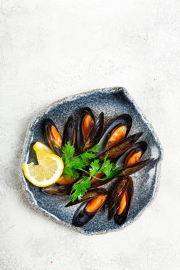 Kabuklu midyeler, kendi sularında kaynatılmış, bir kasede, gri arka planda, üst tarafta, ev yapımı, insan yok.,