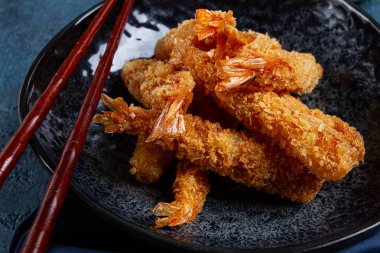 Tempura 'da karides, bol yağda kızartılmış, siyah bir tabakta, soya soslu, yakın çekim, üst manzara, insan yok.,
