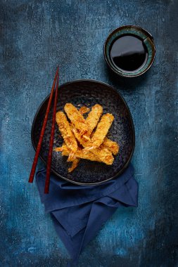Tempura 'da karides, bol yağda kızartılmış, siyah bir tabakta, soya soslu, yakın çekim, üst manzara, insan yok.,
