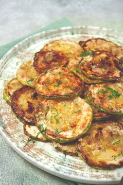 Kızarmış kabak, halka şeklinde kesilmiş, sarımsak ve otlarla, tabakta, üst tarafta, ev yapımı, insan yok.,