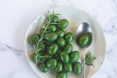 Chalkidiki zeytinleri, klasik Yunan yeşil zeytinleri, bir tabakta, kaşık, üst manzara, insan yok.,