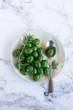 Chalkidiki zeytinleri, klasik Yunan yeşil zeytinleri, bir tabakta, kaşık, üst manzara, insan yok.,