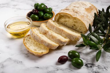 Aperatif, dilimlenmiş ciabatta ekmeği, zeytinyağı, yeşil zeytin, Chalkidiki zeytinleri, klasik yeşil zeytin, mermer bir masada, üst manzara, insan yok.,