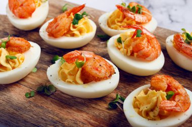 Haşlanmış yumurta sarısı ve mayonezle tatlandırılmış yumurta, karidesle doldurulmuş yumurta, tahta kesme tahtası, seçici odaklanma, yakın plan, insan yok.,