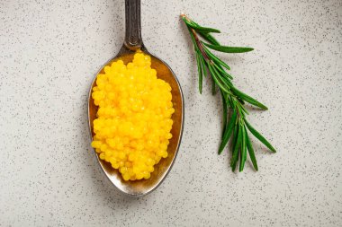 Yuzu havyarı incedir, kaşık üzerinde, üst görünüm, arka plan aydınlık, insan yok..