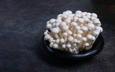 Taze beyaz shimeji mantarları, siyah tabakta, insan yok..