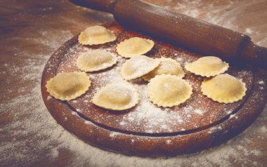Taze çiğ, pişmemiş ravioli, kesme tahtasının üzerinde, hamuru için merdanesi olan, ahşap arka planı olan, insan olmayan,