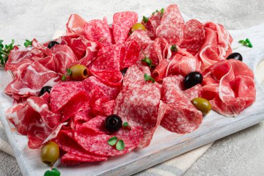Çeşitli, et aperatifi, jambon, salam ve zeytinli, ahşap beyaz bir tahta üzerinde, açık arkaplan, kahvaltı, üst manzara, yakın çekim, insan yok.