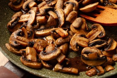 Kızarmış mantarlar tavada, ahşap çatalla, ev yapımı, insan yok.,