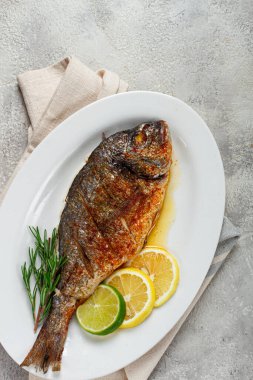 fırında Dorado balığı, fırında, baharat ve otlarla kızartılmış dorado, beyaz bir tabakta, üst manzara, ev yapımı, insan yok.,