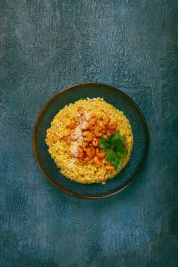 Karidesli risotto, bir kasede, dokulu bir yüzeyde, yanında taze kişniş tabağı, ev yapımı, insan yok.,