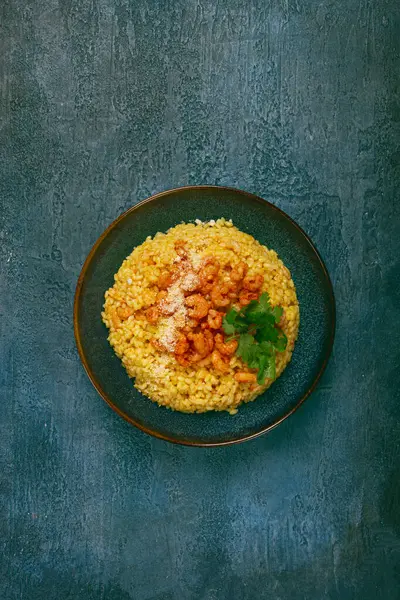 Karidesli risotto, bir kasede, dokulu bir yüzeyde, yanında taze kişniş tabağı, ev yapımı, insan yok.,