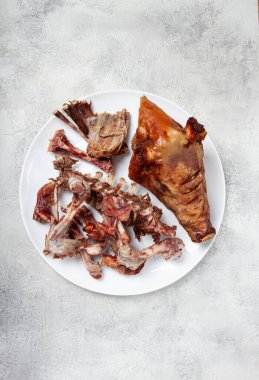 Kızarmış domuz kafası, kemik ve et kalıntıları, beyaz bir tabakta, insan yok, yakın plan.,