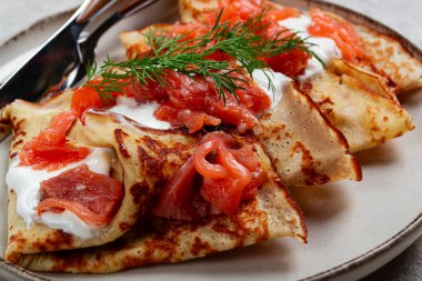 Somon ve ekşi kremalı leziz gözlemeler, kahvaltı tabakta, kırsal tarzda, çatal bıçaklı.