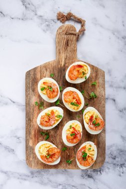 Haşlanmış yumurta sarısı ve mayonezle tatlandırılmış yumurta, karidesle doldurulmuş yumurta, tahta kesme tahtası, seçici odaklanma, yakın plan, insan yok.,