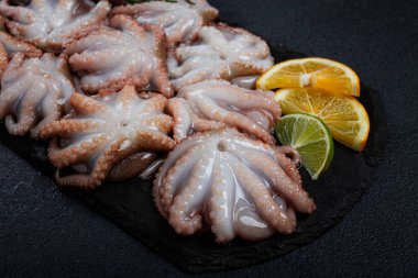 Taze bebek ahtapot, siyah tahtada, limon ve yeşillikle, üst manzara, insan yok.,