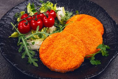 Kızarmış balık pirzolası, balık köftesi, siyah tabakta, taze marul yaprakları, roka ve kiraz domatesleri, ev yapımı, insan yok.,