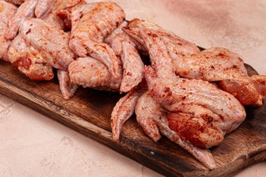 Tavuk kanatları, terbiye edilmiş ve ahşap bir tabakta serilmiş, pişirmeye, ızgara yapmaya ya da pişirmeye hazır, ev mutfağında hiç insan yok.