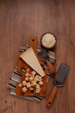 Taze dilimlenmiş ve rendelenmiş peynir, parmesan peyniri, büyük anne hazzı. Grana padano. Ahşap kesim tahtasının üzerinde, köylü tarzı, insan yok.