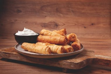 Peynirli kızarmış börek, ahşap bir arka planda, krema soslu, insan yok.,