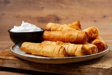 Peynirli kızarmış börek, ahşap bir arka planda, krema soslu, insan yok.,