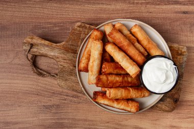 Peynirli kızarmış börek, ahşap bir arka planda, krema soslu, insan yok.,