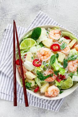 Karides ve pirinç erişteli Tayland salatası, ananas dilimleri, kişniş ve nane yaprakları, beyaz tabakta, ev yapımı, insan yok.,