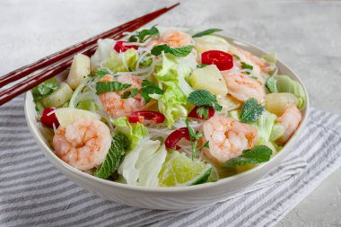 Karides ve pirinç erişteli Tayland salatası, ananas dilimleri, kişniş ve nane yaprakları, beyaz tabakta, ev yapımı, insan yok.,