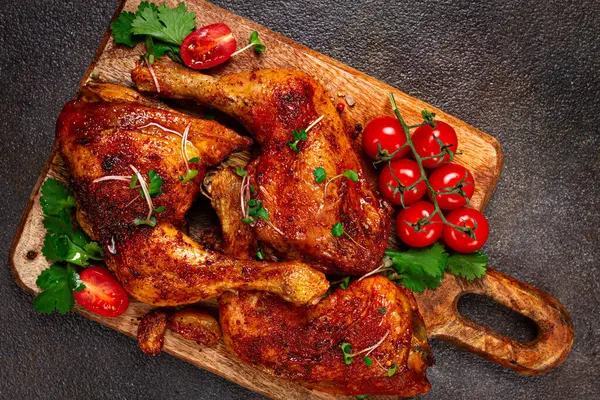 Kızarmış tavuk bacağı, taze kiraz domatesleri ve ahşap kesim tahtasıyla servis edilen otlar, ev yapımı, insan yok.,