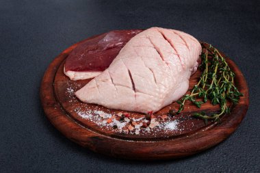 Taze çiğ ördek göğsü, ahşap kesim tahtasının üzerinde, bitkiler ve baharatlarla, insan yok.