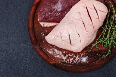 Taze çiğ ördek göğsü, ahşap kesim tahtasının üzerinde, bitkiler ve baharatlarla, insan yok.
