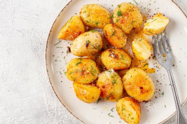 Yarısı yenmiş taze patates, tereyağı ve dereotlu, beyaz bir tabakta, çatalla, evde, insan yok.,