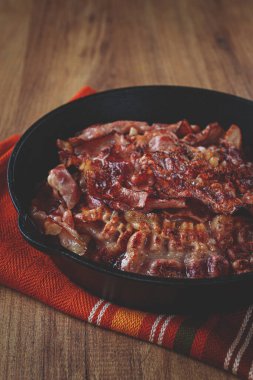 Kavrulmuş domuz pastırması, dökme demir tavada, ahşap bir masada, kırsal tarzda, insan yok.