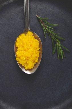 İnci yuzu, yuzu havyarı. Koyu gri bir tabakta, kaşığın üstünde inci. Hiç insan yok..