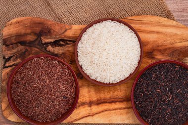 Kırmızı, siyah ve beyaz pirinç seti, bir kâse içinde, ahşap bir yüzey üzerinde, kırsal tarzda, üst manzara